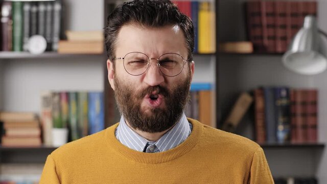Man disgust, abomination, FU, auch emotion. Bearded male teacher or businessman with glasses looking at camera and his face is distorted in disgust. Slow motion