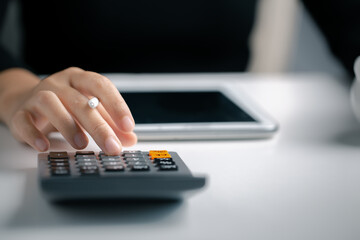 Close up woman hand using calculator and writing make note, calculating financial expense at home office.