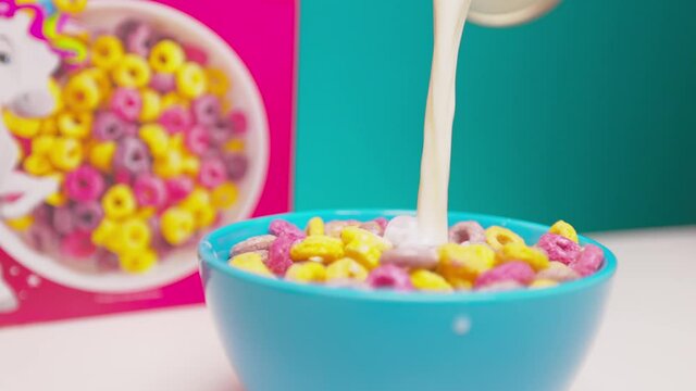 Someone pours milk into a bowl of cereal.