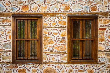 Close-up wall of a stone house with wooden windows and shutters. Old european architecture