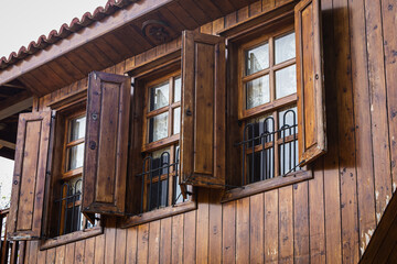 Close-up wall of a wooden house with wooden windows and shutters. Old european architecture