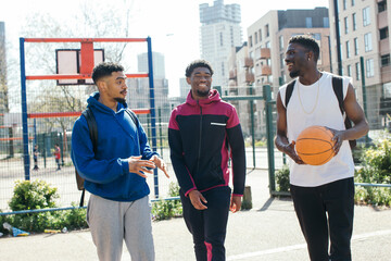 Three men laughing together and leaving basketball court 