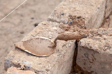 Trowel on wall of unfinished house from raw clay brick