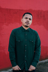 male model with green military t-shirt on a red wall