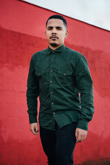 male model with green military t-shirt on a red wall