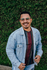 portrait of male model with denim t-shirt on a plant wall