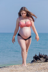 Expectant mother in bikini resting at the sea