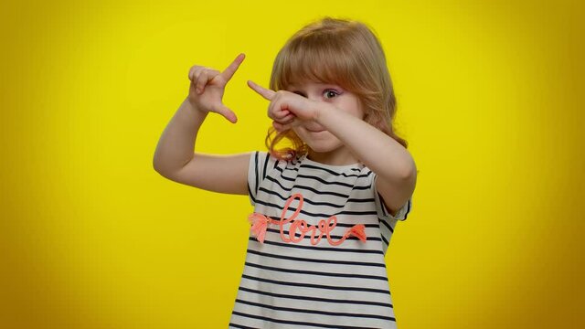 Funny blonde child girl showing loser gesture and pointing on you, blaming accusing for unsuccess, expressing disrespect, mocking your failure on yellow background. Teen kid children bullying abuse