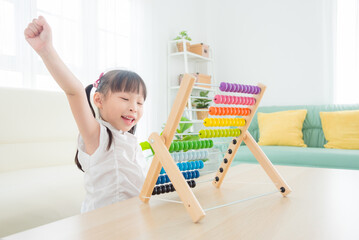 Pretty asian girl playing wood abacus at home. Child education concept.