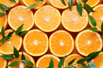 Pieces of fresh oranges with green leaves as background