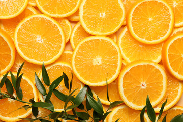 Pieces of fresh oranges with green leaves as background