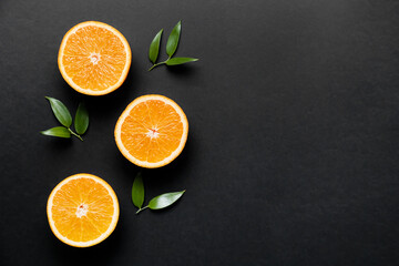 Pieces of fresh oranges with green leaves on dark background