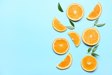Slices of fresh oranges with green leaves on color background