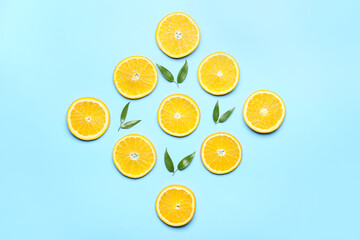 Slices of fresh oranges with green leaves on color background