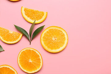 Slices of fresh oranges with green leaves on color background