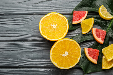 Fototapeta na wymiar Ripe citrus fruits and tropical leaf on dark wooden background