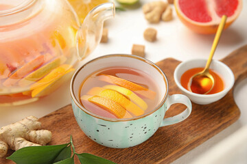 Cup of tasty ginger tea and ingredients on white background, closeup