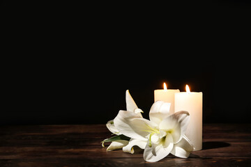 Candles with lily flowers on table against dark background - obrazy, fototapety, plakaty