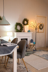 Interior of modern room with fireplace and dining table decorated for Christmas