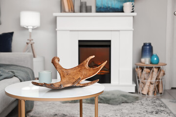 Moose antler on table in interior of room with fireplace