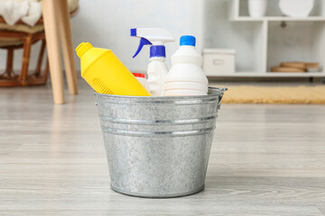 Metal bucket with cleaning supplies in room