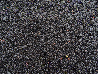 Closeup view of black colored volcanic pebble stones with ground round shape at the famous beach Reynisfjara on the southern coast of Iceland.