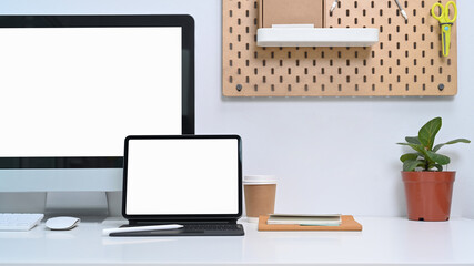 Modern workspace with computer, digital tablet, house plant and office. supplies on white table.