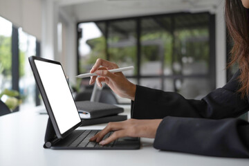 Cropped sho of businesswoman holding stylus pen writing information on computer tablet.