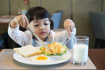 Asian kid having a healthy breakfast in the morning. 