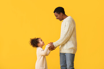 Cute African-American girl greeting her dad on Father's Day against color background