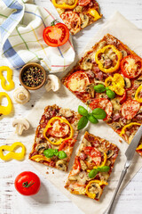 Home made baking. Detroit-Style Pizza. Large rectangular Pepperoni pizza with tomatoes, salami and cheese on a rustic wooden table. Top view. Flat lay.