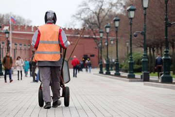 Worker carries a wheelbarrow in the Moscow. Street cleaning and sidewalk repairing in spring city