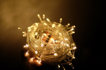 White Christmas lights on an open palm of the hand, Hand holding white/yellow Christmas lights, Long string of Christmas lights on a hand