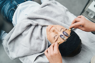 Calm client being massaged with two amethyst face rollers