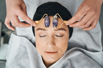 Tranquil spa client being massaged with amethyst face rollers