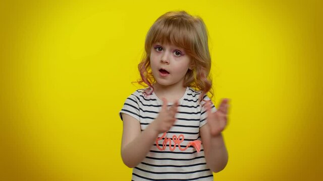 Great work, nice. Portrait of proud funny blonde child girl 5-6 years old in striped t-shirt applauds and nodding in approval, successful good job on yellow studio wall background. Teen kid children