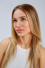 Naklejka premium Large vertical portrait of a woman. Young beautiful blonde in a fashionable white T-shirt on a white background in the studio.
