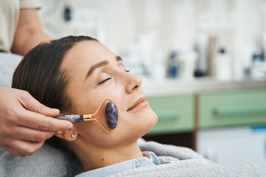 Patient Having Her Cheek Massaged With An Amethyst Roller