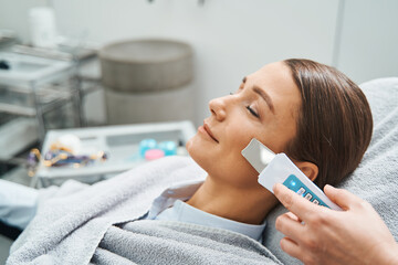 Calm client having her pores cleaned with an ultrasonic scrubber