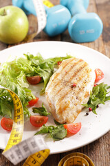 diet food concept with chicken,  vegetables and dumbbell
