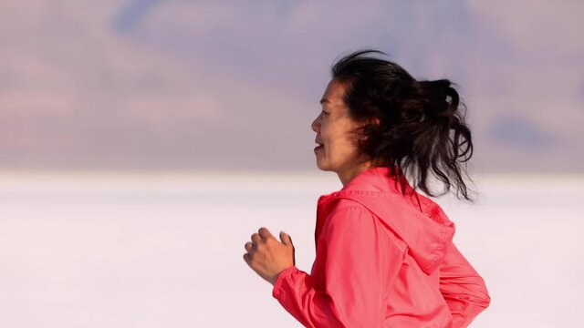 Asian woman jogging across the Bonneville Salt Flats flats in Utah. Slow Motion.