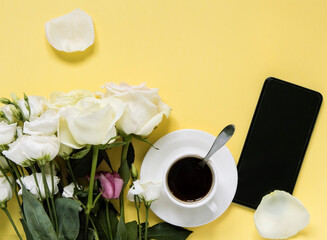 cup of black coffee with flowers and smartphone on yellow background