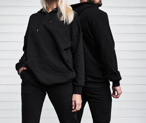 Woman and man wear black hoodie without a logo. No logo basic sportswear. Long sleeve sweatshirt...
