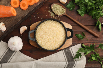 Flat lay composition with dry rice in wok on wooden table