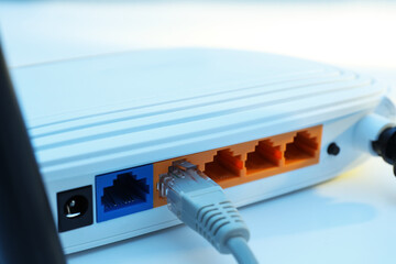 Connected cable to router on white table, closeup. Wireless internet communication
