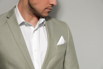Man with handkerchief in breast pocket of his suit on grey background, closeup