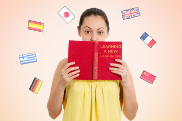 English language Day. A young female student covers her face with a textbook. Beige background with...