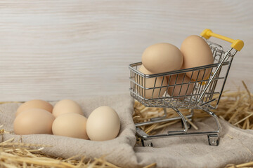 Fresh chicken eggs in straw on a mini shopping cart. Online delivery concept for farm organic eggs. Copy space.
