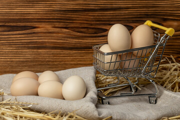 Fresh chicken eggs in straw on a mini shopping cart. Online delivery concept for farm organic eggs. Copy space.