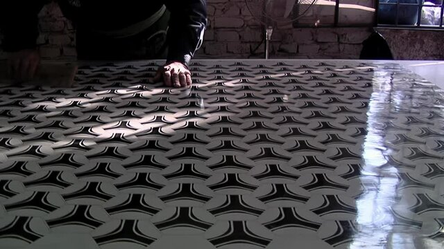 Worker wiping Dust from a Synthetic Leather Laminate inside a Soccer Ball Factory. Low Angle View. 